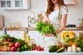 Young happy woman holding lettuce leaves for making salad in the beautiful kitchen with green fresh ingredients indoors. Healthy Royalty Free Stock Photo