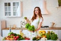 Young happy woman holding lettuce leaves for making salad in the beautiful kitchen with green fresh ingredients indoors. Healthy Royalty Free Stock Photo