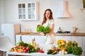 Young happy woman holding lettuce leaves for making salad in the beautiful kitchen with green fresh ingredients indoors. Healthy Royalty Free Stock Photo