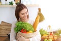 Young happy woman holding paper bag full of vegetables and fruits while smiling. Girl have made shopping and ready for Royalty Free Stock Photo