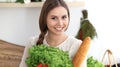 Young happy woman holding paper bag full of vegetables and fruits while smiling. Girl have made shopping and ready for Royalty Free Stock Photo