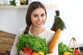 Young happy woman holding paper bag full of vegetables and fruits while smiling. Girl have made shopping and ready for Royalty Free Stock Photo