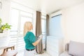 Young Happy Woman Holding Remote Control Air Conditioner In House. Royalty Free Stock Photo