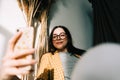 Young happy woman holding smartphone looking on cell using mobile phone technology at home, taking selfie for social media or Royalty Free Stock Photo