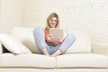Young happy woman on home sofa using internet app on digital tablet pad Royalty Free Stock Photo