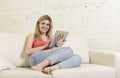 Young happy woman on home sofa using internet app on digital tablet pad Royalty Free Stock Photo