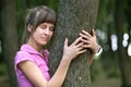 Young happy woman hugging big tree trunk in summer park Royalty Free Stock Photo