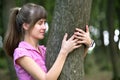 Young happy woman hugging big tree trunk in summer park Royalty Free Stock Photo
