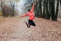 Young happy woman jumping in autumn park. Fitness girl training outside on a warm fall day Royalty Free Stock Photo