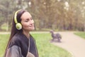 Young happy woman listening music from smartphone with headphones in a quiet Park Royalty Free Stock Photo