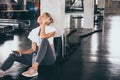 Young happy woman listening to music by smartphone while having exercise break at the gym Royalty Free Stock Photo