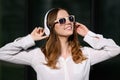 Young happy woman listens to music in white wireless headphones while walking around the city on a sunny day. Royalty Free Stock Photo