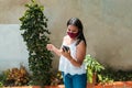 Young and happy woman with mask and casual clothes and smartphone in hand, having fun and dancing while resting at home