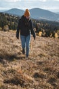 Young happy woman in orange beanie is walking in front of mountains landscape Royalty Free Stock Photo