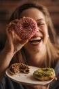 Young happy woman posing with donuts in a cafe. Royalty Free Stock Photo