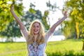 Young happy woman raising hands outdoors