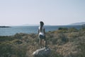 Young happy woman with rasta stands on to the rock. Traveler enj