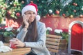 Smiling woman in Santa hat talking on her phone in cafe outside