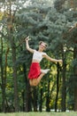 A young happy woman in a red skirt jumps high in a summer park, having fun Royalty Free Stock Photo