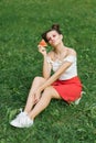A young happy woman in a red skirt and a white T-shirt blows a kiss while holding a watermelon in her hand Royalty Free Stock Photo