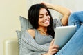 Young happy woman resting on a sofa with tablet computer Royalty Free Stock Photo