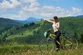 Young happy woman riding bicycle in the mountains at summer day Royalty Free Stock Photo