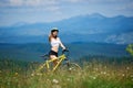 Young happy woman riding bicycle in the mountains at summer day Royalty Free Stock Photo