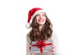 Young happy woman in santa hat looking sideways showing Christmas present. Royalty Free Stock Photo