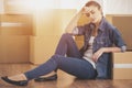 The young happy woman sits in a room near boxes. Moving, purchase of new habitation
