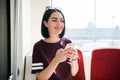 Young happy woman sitting in city bus and using her mobile phone. Royalty Free Stock Photo