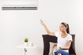 Young Happy Woman Sitting On Couch Operating Air Conditioner With Remote Control At Home Royalty Free Stock Photo