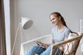 Young happy woman sitting on cozy chair and using digital tablet, relaxing concept Royalty Free Stock Photo