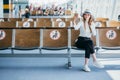 Young happy woman sitting at the gate and using smartphone while waiting for a flight at the airport. Travel concept Royalty Free Stock Photo