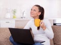 Woman with laptop and cup of coffee on sofa Royalty Free Stock Photo