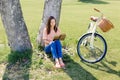 Young happy woman sitting under tree with book Royalty Free Stock Photo