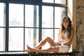 Young happy woman sitting on a window-sill and looking outside Royalty Free Stock Photo