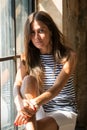 Young happy woman sitting on a window-sill and looking outside Royalty Free Stock Photo