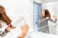 Happy woman smiling and drying her hair with hairdryer near the mirror in the bathroom Royalty Free Stock Photo