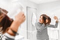 Happy woman smiling and drying her hair with hairdryer near the mirror in the bathroom Royalty Free Stock Photo