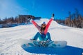 Young happy woman snowboarder sits on on a snowy mountain slope Royalty Free Stock Photo