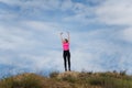 Young happy woman in sportswear standing on hill with arms up to sky. Fitness, healthy way of life, wellbeing, freedom Royalty Free Stock Photo