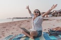 Young happy woman in sunglasses sitting on the beach with laptop, freelancer with open arms, remote work concept Royalty Free Stock Photo