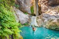 Young happy woman swimming in turquoise blue crystal clear water in the river with a waterfall summer vacation relaxing Royalty Free Stock Photo