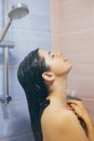 Young happy woman taking hot shower at home or hotel bathroom. Beautiful  brunette girl washing her hair and enjoying relax time. Royalty Free Stock Photo