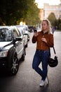 Young happy woman taking new photos on smartphone on the street. Girl doing selfies for social nets on the road with Royalty Free Stock Photo