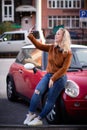 Young happy woman taking new photos on smartphone on the street. Girl doing selfies for social nets on the road with Royalty Free Stock Photo