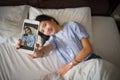 young happy woman taking selfie with mobile phone in bedroom morning. Royalty Free Stock Photo