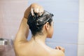 Young happy woman taking shower at home or hotel bathroom. Beautiful  brunette girl washing her hair and enjoying relax time. Body Royalty Free Stock Photo