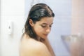 Young happy woman taking shower at home or hotel bathroom. Beautiful  brunette girl washing her hair and enjoying relax time. Body Royalty Free Stock Photo