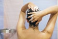 Young happy woman taking shower at home or hotel bathroom. Beautiful  brunette girl washing her hair and enjoying relax time. Body Royalty Free Stock Photo